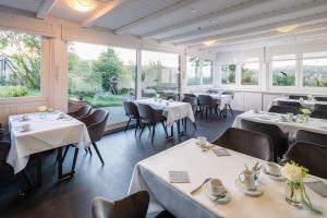 un restaurante con mesas, sillas y ventanas grandes en Hotel Görtler, en Seesen