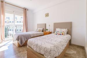 two beds in a room with a window at MalagaSuite Torremolinos Lovely & Comfy in Torremolinos