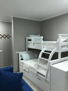 a bedroom with white bunk beds and a blue couch at LukasSaloMea in Borjomi
