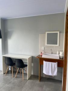 a bathroom with a sink and a table and two chairs at Vista da Serra. in Gramado