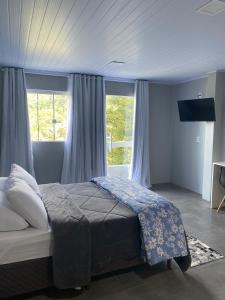 a bedroom with a large bed with blue curtains at Vista da Serra. in Gramado