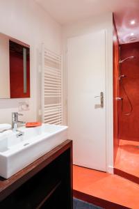 La salle de bains est pourvue d'un lavabo blanc et d'une douche. dans l'établissement La Maison des Courtines, à Beaune