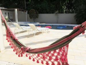 a hammock in front of a pool with two chairs at Casa para familia em Riviera, com WiFi in Bertioga