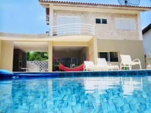 a house with a swimming pool in front of a house at Casa para familia em Riviera, com WiFi in Bertioga