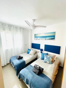 a bedroom with two beds and a ceiling fan at Seafront La Manga Apartment in La Manga del Mar Menor