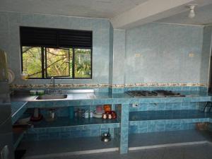 W apartamencie znajduje się wyłożona niebieskimi kafelkami kuchnia ze zlewem i oknem. w obiekcie Encantadora Finca privada con piscina, El Mirador w mieście Fusagasugá