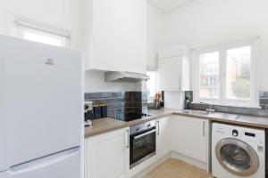 a kitchen with white cabinets and a washer and dryer at Lovely, modern & spacious 1-bed flat central Hove in Brighton & Hove