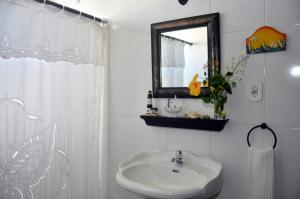 Baño blanco con lavabo y espejo en ANGEL'S SEA Pousada en Rio das Ostras