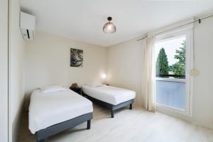 two beds in a room with a window at Garden & City Aix En Provence - Puyricard in Aix-en-Provence