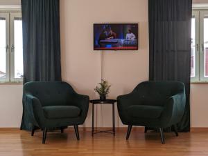 クリスティーネハムンにあるHotell Broの壁にテレビが付いた客室内の緑の椅子2脚