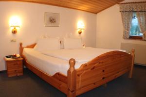 Schlafzimmer mit einem Holzbett mit weißer Bettwäsche in der Unterkunft Landhaus Johanna in Dorfgastein