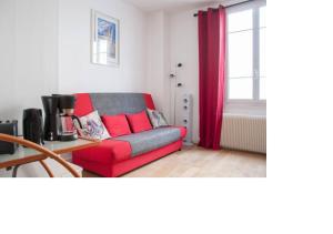 a living room with a red couch and a window at La petite maison parisienne in Levallois-Perret