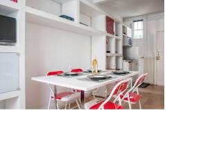 uma cozinha com uma mesa branca e cadeiras vermelhas em La petite maison parisienne em Levallois-Perret