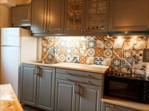 a kitchen with gray cabinets and a tiled wall at Diminio 3 Apartment at Livadi Arachova in Arachova