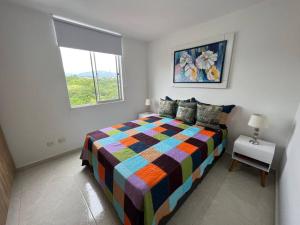 Un dormitorio con una cama colorida y una ventana en HERMOSO APTO CON VISTA a LAS MONTAÑAS DEL QUINDÍO CERCA de TODO, en Armenia