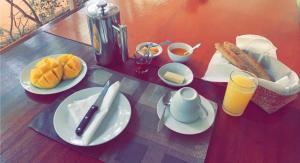 a table topped with plates of food and orange juice at Villa Bobo in Bobo-Dioulasso