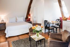 um quarto com uma cama, uma mesa e cadeiras em La Maison des Courtines em Beaune