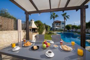 una mesa con comida junto a una piscina en Ifigeneia's Luxury Resort with Private Hot Tub, en Kalathas