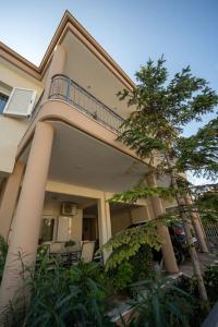 a house with a balcony and a tree in front of it at Alexandros Suite in Tríkala