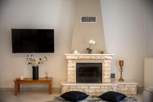 a living room with a fireplace and a flat screen tv at Alexandros Suite in Tríkala