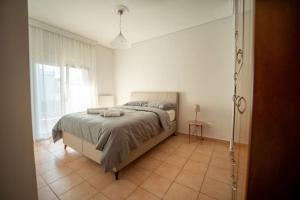 a bedroom with a large bed in a white room at Alexandros Suite in Tríkala