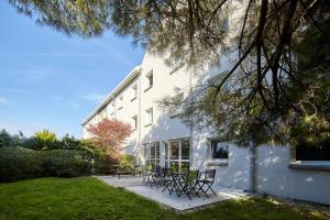 un edificio blanco con mesas y sillas en un patio en B&B HOTEL Evry Lisses 2, en Lisses