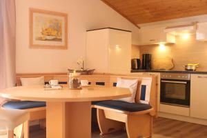 eine Küche mit einem Holztisch, Stühlen und einem Tisch in der Unterkunft Landhaus Johanna in Dorfgastein