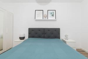 a white bedroom with a large bed with blue sheets at Casa do Nilo in Sesimbra