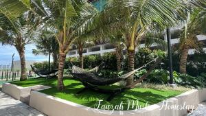 two hammocks on a lawn with palm trees in front of a building at Bali Residences by Fauzah Muslim Homestay in Melaka