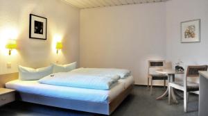 a hotel room with a large bed and a table at Hotel Garni Haus Dornheim in Obertshausen