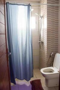 a bathroom with a toilet and a blue shower curtain at DALOU Chambre hôte, Cité mixta in Dakar
