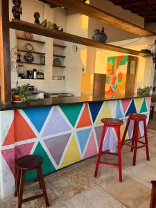 a kitchen with a colorful counter and two stools at Amelinhas House in Jericoacoara