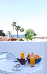 a table with a bowl of fruit and two glasses of juice at Paspalis Hotel in Skala Kefalonias