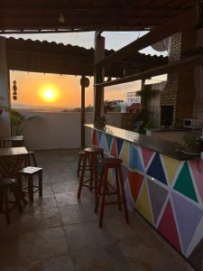 a bar with stools and the sunset in the background at Amelinhas House in Jericoacoara