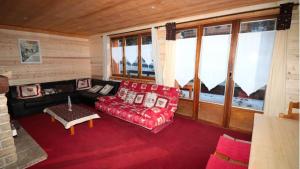 salon z czerwoną kanapą i oknami w obiekcie CHALET L'Eyssinette Appartement 8 a 10 couchages w mieście Vars