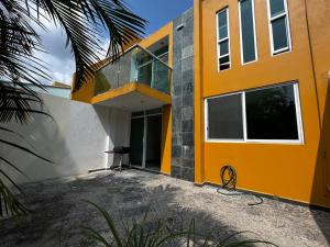 a yellow house with a glass balcony on it at Casa Lían in Cuernavaca