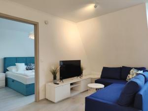 a living room with a blue couch and a tv at Sunshine Residence Deluxe Apartment in Hévíz