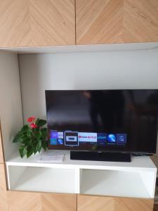 TV de pantalla plana en un estante blanco en Apartament Imara-klimatyzacja, miejsce parkingowe, en Łódź