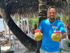 a man holding two coconuts on a beach at Hotel ECOLODGE LE RAVORAHA in Sainte Marie