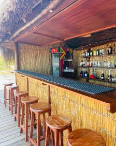 a bar with a row of wooden stools and a counter at Mangal Beach Lodge in Vilanculos