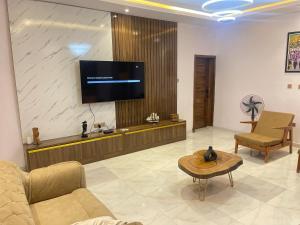 a living room with a couch and a tv on a wall at Villa Sofia in Abeokuta