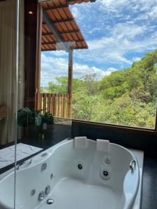 a bath tub in a room with a large window at Pousada Vereda da Serra in Pirenópolis