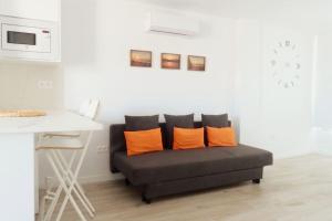 a couch with orange pillows in a living room at Newly refurbished beachfront apartment. in San Bartolomé de Tirajana