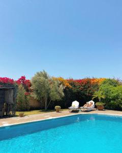 einen Pool mit zwei Gartenstühlen in der Unterkunft Maison Mimosa, lovely 3 bedroom villa with a heated pool in Essaouira