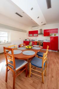 uma cozinha com mesa, cadeiras e armários vermelhos em Apartman Lega - Daruvar em Daruvar