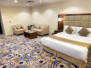 une chambre d'hôtel avec un grand lit et des chaises dans l'établissement Al Jury Residence Hotel Suites, à Khobar