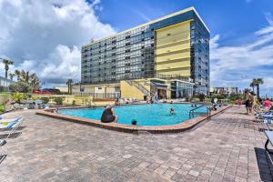 a woman sitting in front of a swimming pool in front of a building at Beachfront Daytona Studio, Close to Parks! in Daytona Beach