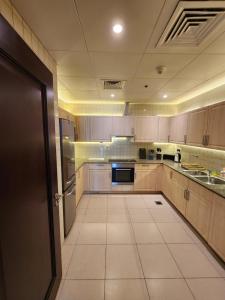 a large kitchen with wooden cabinets and a refrigerator at Luxurious 2-bedroom Apartment with Sea View in Doha
