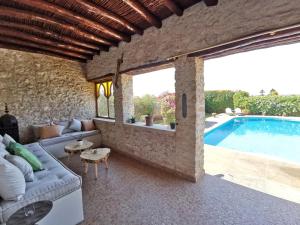 ein Wohnzimmer mit einem Sofa und einem Pool in der Unterkunft Maison Mimosa, lovely 3 bedroom villa with a heated pool in Essaouira
