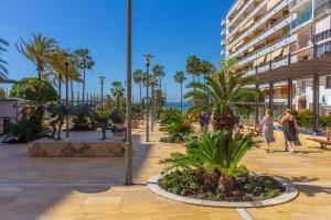 people walking around a park with palm trees and a building at XPCE MARINO 2 MARBELLA in Marbella